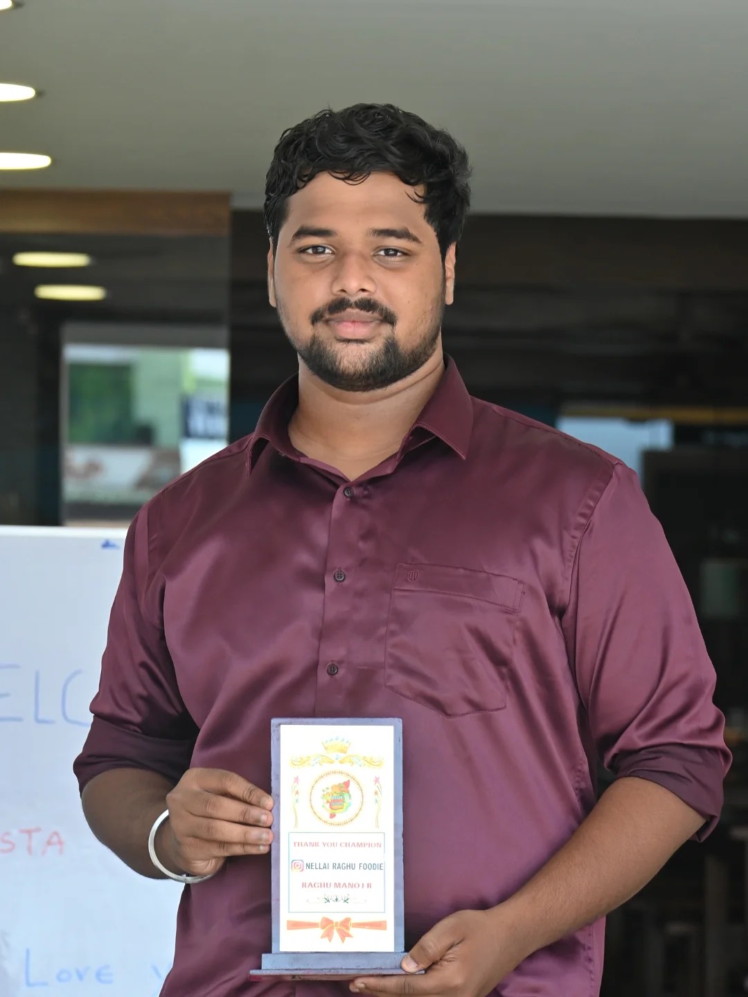 Raghu Manoj holding appreciation trophy